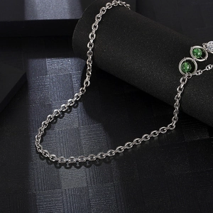 Minimalist titanium steel chain necklace with green and white beads on black stand