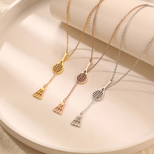 Three badminton racket and birdie necklaces in gold, rose gold, and silver on white props