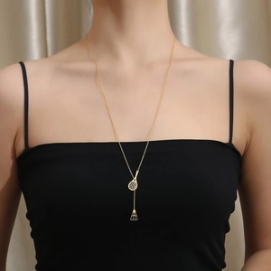 Detail shot of a lady wearing an 18K gold badminton racket and birdie pendant necklace