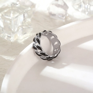 Macro detail of silver cuban link ring with black enamel drips and polished steel texture