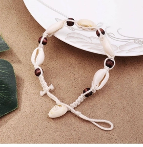 Close-up of handmade shell and wood bead anklet with bohemian braided cotton cord