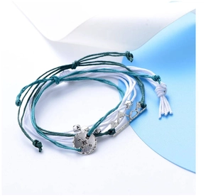 Detail of bohemian braided cord bracelets featuring silver compass and mountain charms
