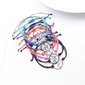 Detail of colorful handmade wax cord bracelets with wave charms and adjustable braids