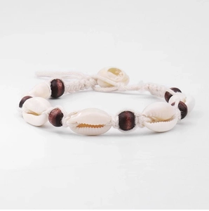 Detailed close-up of handmade bohemian wood bead and natural cowrie shell ankle bracelet