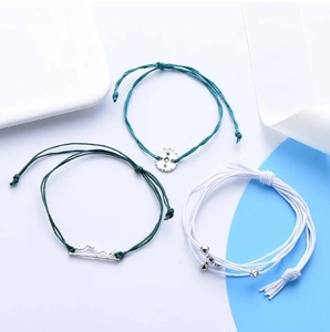 Detail showing bohemian woven bracelets with compass and mountain pendants on white background