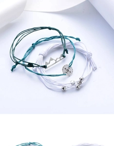 Detail of woven rope bracelets with mountain pendant and compass charms in silver