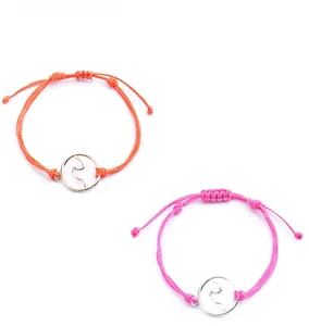 Detail of colorful wax string bracelets with silver surfing wave charm and adjustable knot