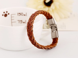 Détail d'un bracelet en cuir tressé marron avec fermoir métallique sur un fond artistique