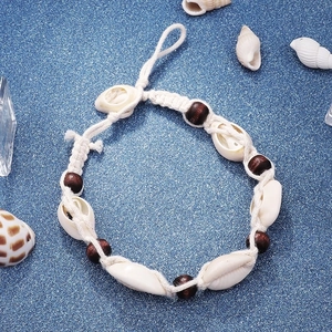 Bohemian seashell and wood bead anklet for summer beach vacations on dark blue background