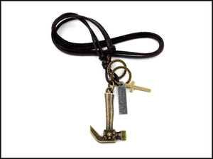 Detail of punk leather cord necklace featuring bronze hammer, cross, and engraved charms