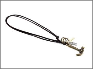 Detailed view of punk leather necklace with bronze hammer, cross and engraved metal charms