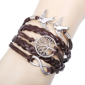 Gros plan d'un bracelet multicouche en cuir avec pendentifs arbre de vie et oiseaux