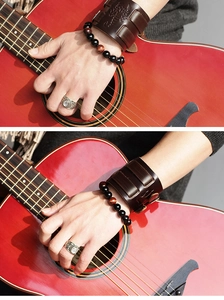 Detail of vintage scorpion leather cuff, beaded bracelet and ring set with red guitar