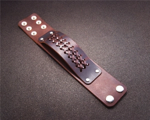 Detail view of brown braided leather bracelet with silver metal rivets and double snap button