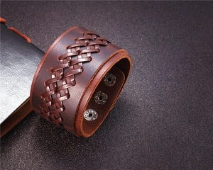 Detail of vintage brown leather bracelet with woven texture and silver metal snap buttons
