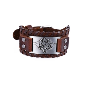 Macro detail of leather bracelet featuring a silver dragon plaque and Celtic knots