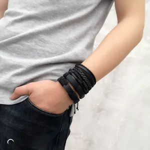 Detail of multi-layer black braided leather bracelet set on male wrist for casual style