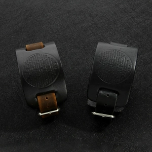 Macro view of leather wristbands with vintage engraved metal compass and prayer details