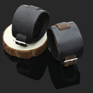 Close-up of wide leather bracelets with Lord's Prayer engraving and metal buckles