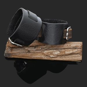 Close-up of vintage black leather bracelet with embossed Lord's Prayer on a wood log