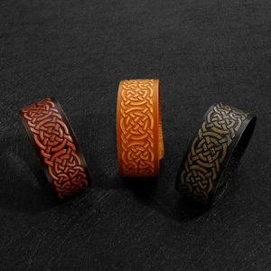 Detailed close-up of wide leather bracelets with embossed Celtic knot patterns in three colors