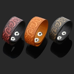 Detail of three leather bracelets with embossed dragon patterns and metal snap buttons