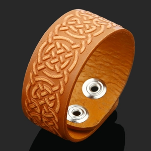 Macro detail of brown leather cuff bracelet featuring embossed Celtic knot patterns and silver snaps