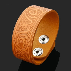 Macro detail of Tree of Life embossing on brown leather cuff with silver metal snaps