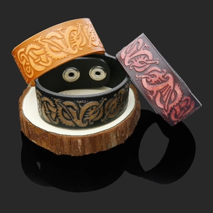 Detail view of wide leather Viking bracelets with dragon embossing in black, brown and burgundy