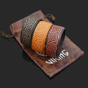 Detailed view of three vintage Viking leather bracelets with embossed Celtic knots on a pouch