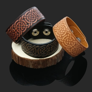 Three colors of punk leather bracelets with Celtic knot embossing on wooden stand