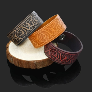 Detailed macro view of vintage Viking Tree of Life embossed leather bracelets with metal snaps