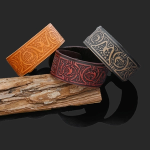 Detailed view of embossed Celtic patterns on wide leather bracelets in three vintage colors