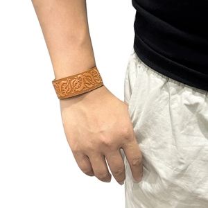 Men's wide brown leather bracelet with Nordic Viking dragon pattern on a male wrist