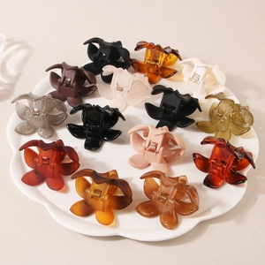 Flat lay of small butterfly hair claws in multiple colors on white ceramic plate
