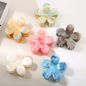 Flat lay of six colorful gradient flower claw clips in acetate marble texture for women