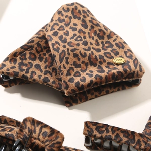 Detail of leopard print hair claw clip featuring velvet texture and gold metal plaque