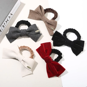 Détail de cinq chouchous à nœuds en maille et velours avec des boucles dorées élégantes