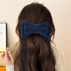Détail d'une pince à cheveux en velours bleu marine avec un grand nœud multicouche