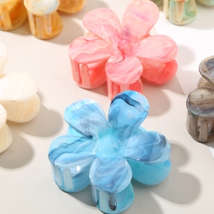 Close-up of marble pattern acetate flower hair claws in multiple soft pastel colors