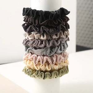 Set of 8 premium satin scrunchies in various neutral colors on a white display stand