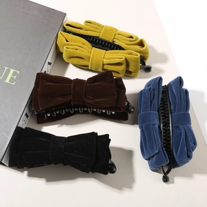 Dettaglio di quattro mollette banana in velluto nei colori giallo, marrone, nero e blu