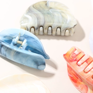 Detail of marble pattern acetate hair claws with gold metal springs and smooth teeth