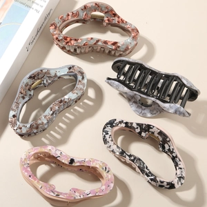 Flat lay of five large acetate hair claw clips with marble and floral patterns