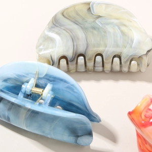 Close-up of marble texture hair claws in blue, grey and orange with smooth finish