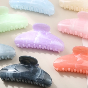 Macro shot of large hair claws with cream marble texture in assorted pastel colors