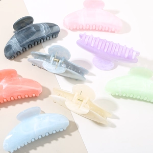 Detailed close-up of marble-textured acetate hair claws in various elegant pastel colors