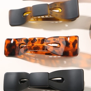 Gros plan de grandes barrettes à nœud en écaille, ambre et noir mat élégant