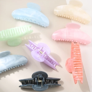 Macro detail of marbled acetate hair claws showing glossy texture and elegant pastel patterns