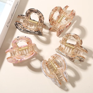 Macro view of five colorful heart-shaped acetate hair claw clips with gold metal springs